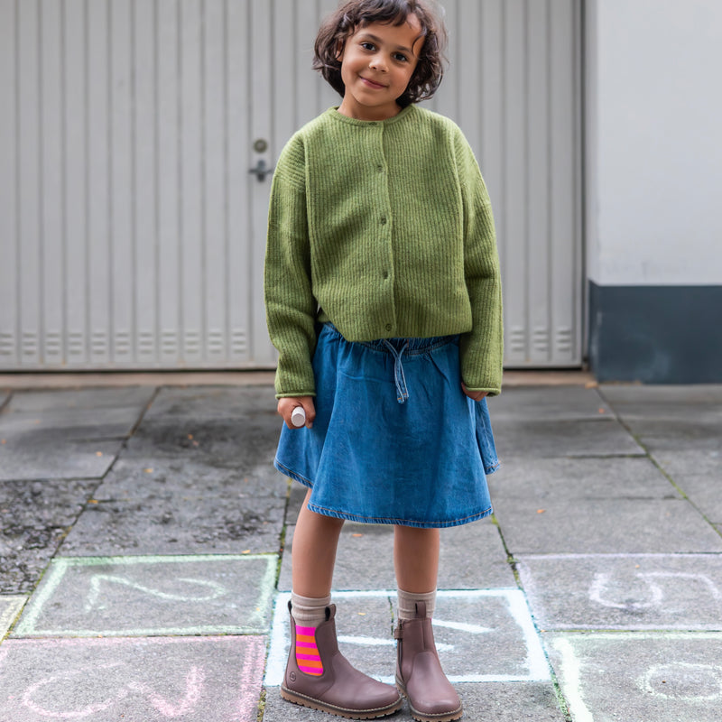 Girl in a denim skirt and green cardigan wearing the pink and orange Chelsea Boot
