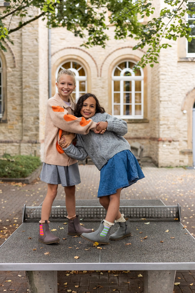 Two girls hugging on a ping-pong table in Chelsea boots