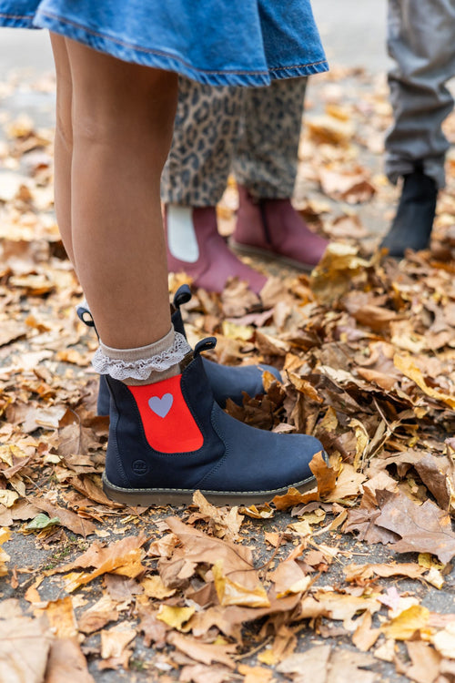 Navy Chelsea boot with a red heart panel, worn with lace socks in fall leaves