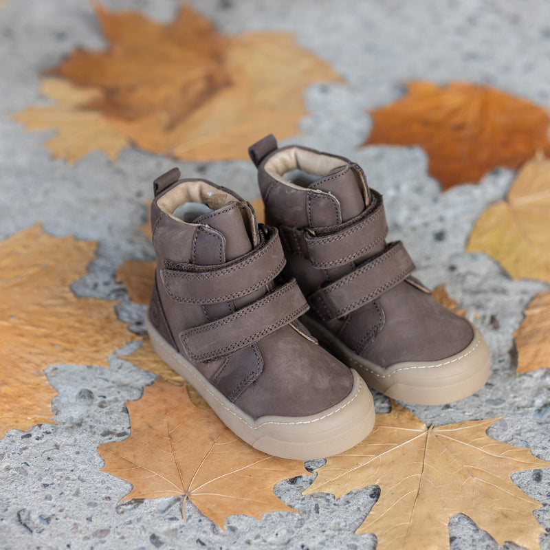 A pair of brown First Step Boots resting on fall leaves