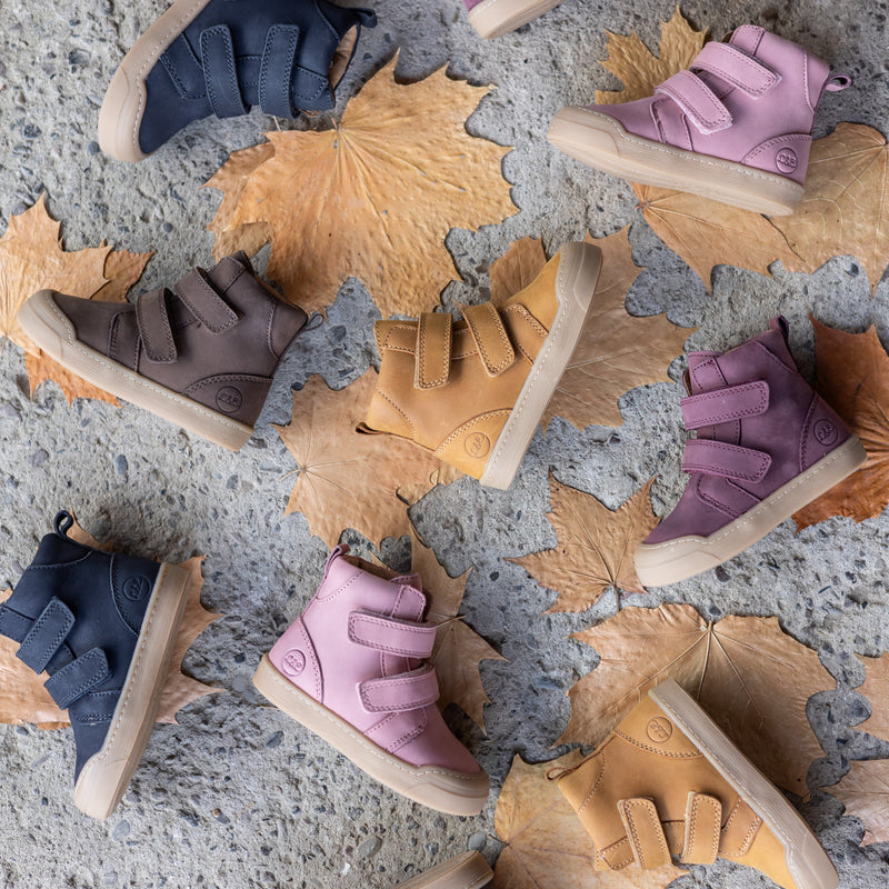 The First Step Boot shown in several colors on fall leaves