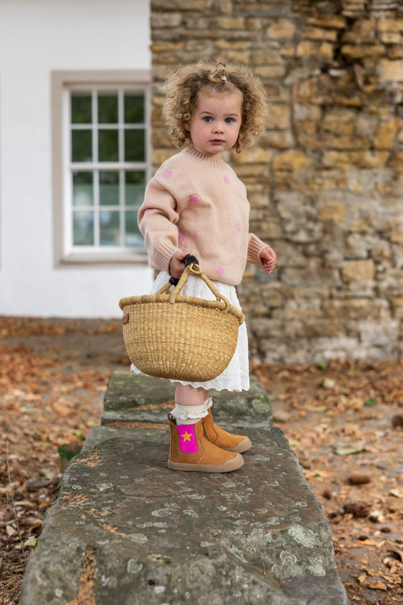 Toddler with a basket wearing the Winter Janne Bootie in camel and star