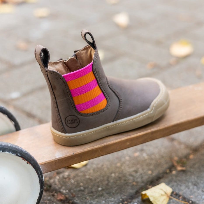 Janne bootie with a pink and orange striped panel on a wooden plank